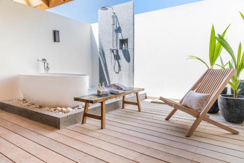 a bath tub in a bathroom with a chair and a bath tub at Kagi Maldives Resort & Spa in North Male Atoll