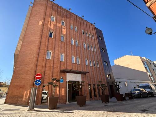 ein hohes rotes Backsteingebäude an einer Straßenseite in der Unterkunft Hotel Nova Roma in Merida
