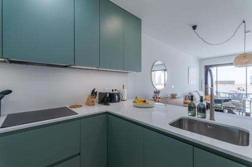 a kitchen with green cabinets and a sink at LA Paz - Sunny Pool Retreat - Jacuzzi - Near Beach in Los Alcázares