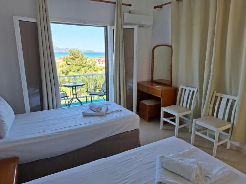 a hotel room with two beds and a view of the ocean at Cleopatra Apartments in Laganas