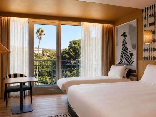 a hotel room with two beds and a large window at Mercure Nice Promenade Des Anglais in Nice