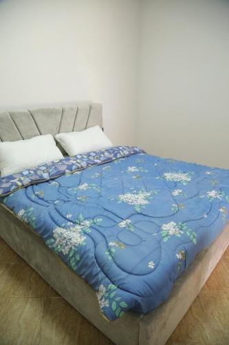 a bed with a blue blanket with flowers on it at Prim Guest House in Këlcyrë