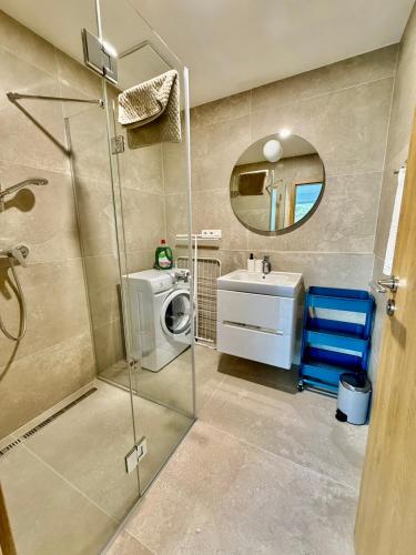 a bathroom with a shower and a sink and a washing machine at Ager Apartments Poprad in Poprad