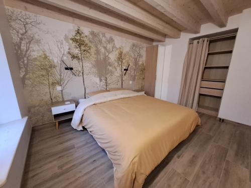 a bedroom with a bed and a wall with trees at La remise de Saussenigoutte in Cornimont