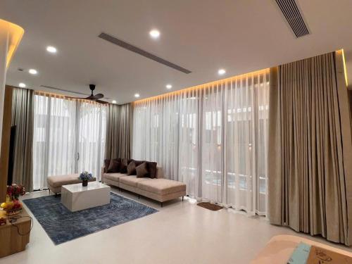 a living room with a couch and large windows at La Vida Residences Villa in Ấp Phước Thánh