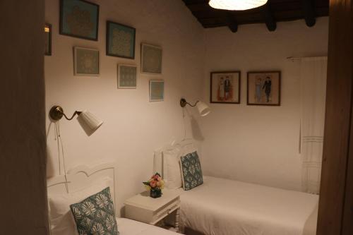 a room with two beds and two lamps and pictures on the wall at C M Casa de Mares Alojamento Local in Casas Novas de Marés