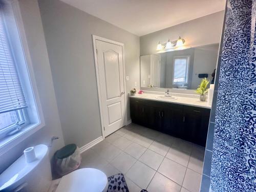 a bathroom with a toilet and a sink and a mirror at Cozy Beautiful Home in Brampton
