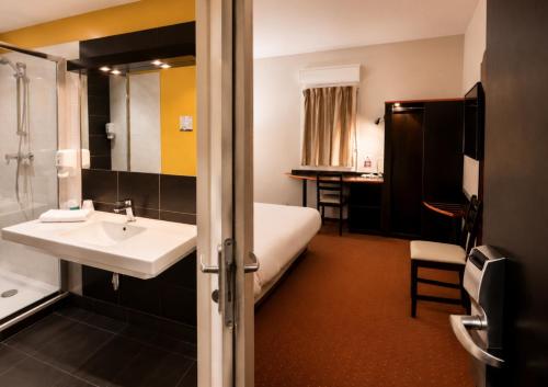 a bathroom with a sink and a bed and a shower at Hôtel Restaurant Akena Bordeaux Sud - La Brède in La Brede