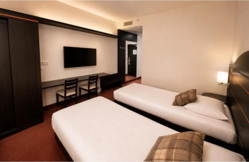 a hotel room with two beds and a flat screen tv at Hôtel Restaurant Akena Bordeaux Sud - La Brède in La Brede