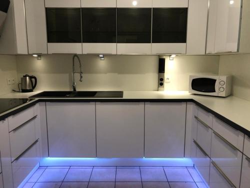 a kitchen with white cabinets and a blue light at Disney golden house in Magny-le-Hongre