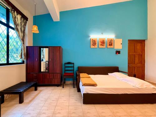 a bedroom with two beds and a blue wall at Bijou Guest House in Baga