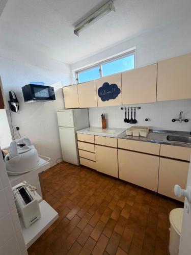 a kitchen with white cabinets and a sink and a toilet at Marachique Beach Flat in Alvor