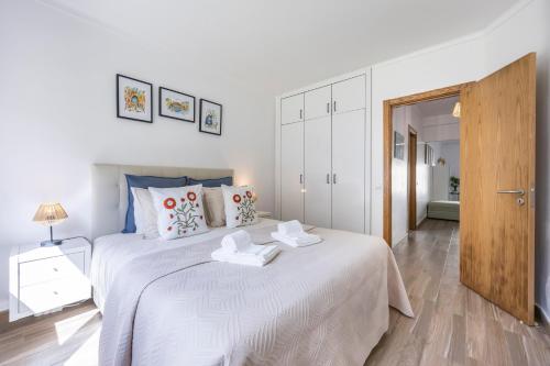 a white bedroom with a large white bed with towels on it at T1 Morderno - Alvor in Alvor