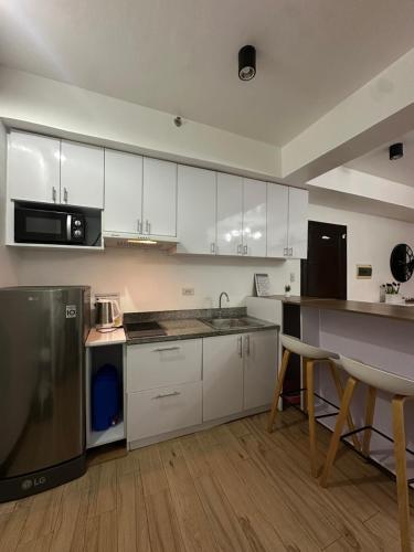 a kitchen with white cabinets and a black refrigerator at MK Suites CDO in Pontud