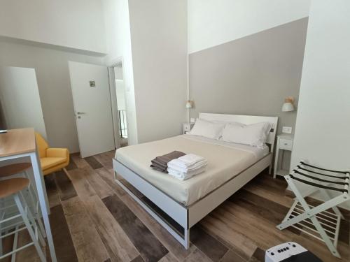 a white bedroom with a bed and a chair at B&B La Piccola Lepre in Acqui Terme