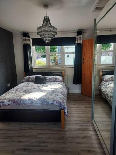 a bedroom with a bed and two windows and a chandelier at Beautiful 1-Bed Apartment in Sandy in Sandy