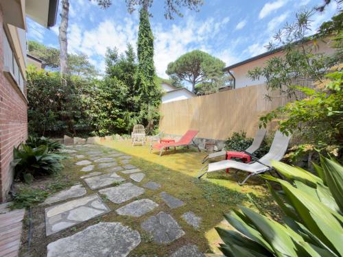 a backyard with two chairs and a stone pathway at Villa Tamerici - Garden & Parking in Lignano Sabbiadoro