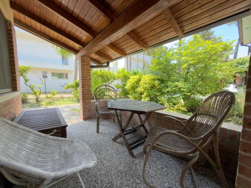 a patio with chairs and a table and a table and chairs at Villa Tamerici - Garden & Parking in Lignano Sabbiadoro
