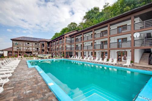 a large swimming pool in front of a building with chairs at Dallas in Solotvyno