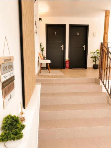 a hallway with three black doors and a staircase at Elysian apartment 1 in Trenčín