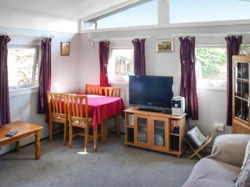 a living room with a table and a television at Noddfa in Newcastle Emlyn
