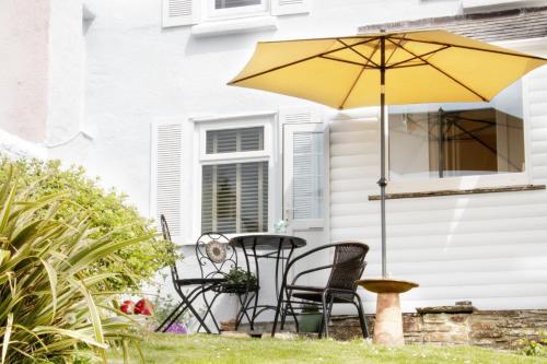 a patio with a table and chairs and an umbrella at Summers Beach View in Saint Mawes