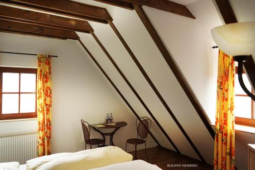 フォイヒトヴァンゲンにあるラント - ガスト - ホフ ヴァルクミューレの屋根裏にテーブルと椅子が備わるベッドルーム1室