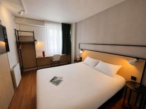 a bedroom with a white bed with a magazine on it at ibis Alençon in Alençon