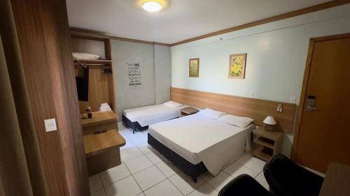 a hotel room with two beds and a desk at CRCN - Golden Dolphin Grand Hotel in Caldas Novas