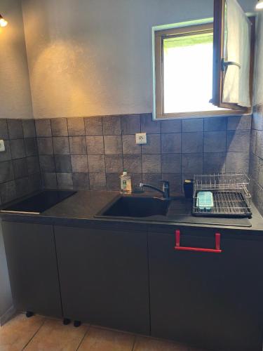 a kitchen counter with a sink and a window at Gîte la Forterie in Linières-Bouton