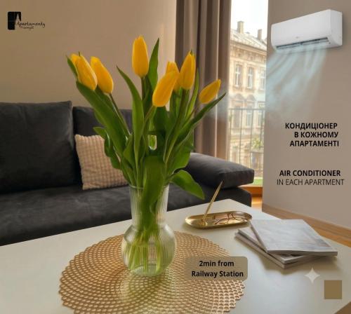a vase filled with yellow tulips sitting on a table at Apartamenty Przemyśl in Przemyśl