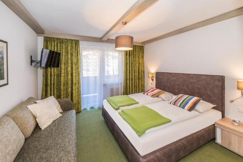 1 dormitorio con 1 cama y 1 sofá en Hotel Garni Wieshof en Rauris