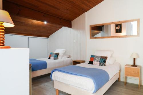 two beds in a room with white walls and wooden ceilings at Logis Hotel & Restaurant Bergeret Sport in Hendaye
