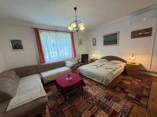 a living room with a couch and a bed at Flóra Apartmanok in Parádsasvár