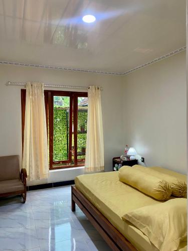 a bedroom with a bed and a window and a chair at Sekar Homestay in Bantul