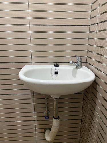 a white sink in a bathroom with striped walls at Sekar Homestay in Bantul