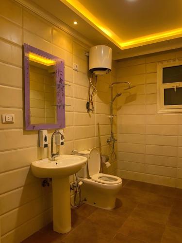 a bathroom with a sink and a toilet and a mirror at Royal Hostgram and Suites in Cairo