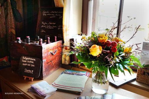 a vase of flowers on a table with a window at Land-Gast-Hof WALKMÜHLE in Feuchtwangen