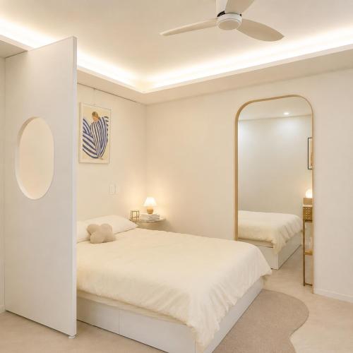 a white bedroom with a bed and a mirror at 포포스테이 in Busan