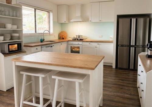 a kitchen with white cabinets and a island with stools at 100m to Beach&Shop Spacious Pristine One Story Family Home in Batemans Bay