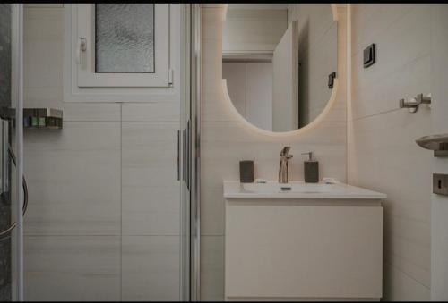 a bathroom with a sink and a mirror and a shower at Dimitra Suites in Pythagoreio