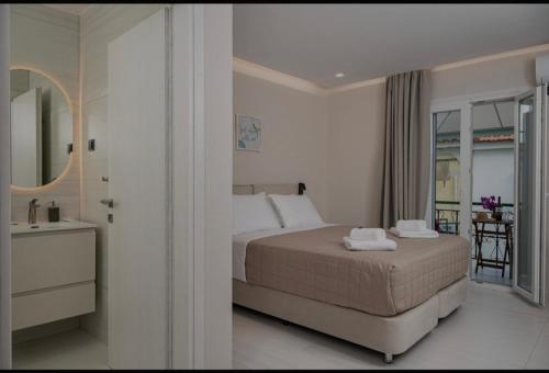 a white bedroom with a bed and a balcony at Dimitra Suites in Pythagoreio