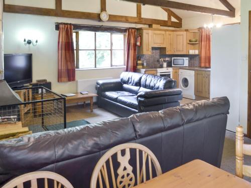 a living room with a leather couch and a kitchen at Great Meadow in Kelly