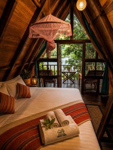 a bedroom with a bed with towels and an umbrella at Wilpattu Green Cabin in Achchamulai