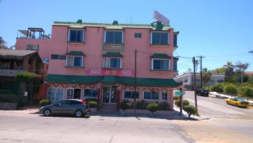 ein rosafarbenes Gebäude mit einem davor geparkt in der Unterkunft Hotel Pekin in La Paz