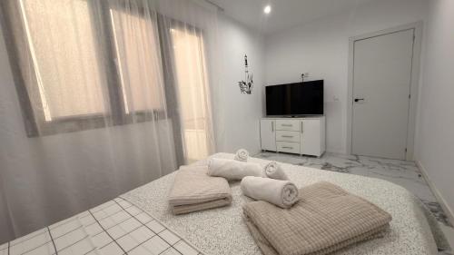 a white room with a bed with towels and a television at Victory in Alicante