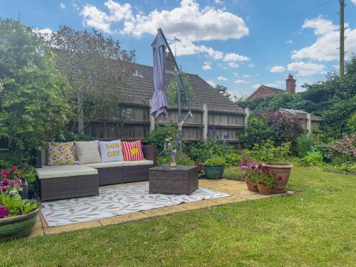 a patio with a couch and an umbrella in a yard at The Other House in Briston