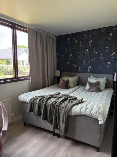 a bedroom with a large bed with a blue wall at Seaside Stay Haverdal in Haverdal