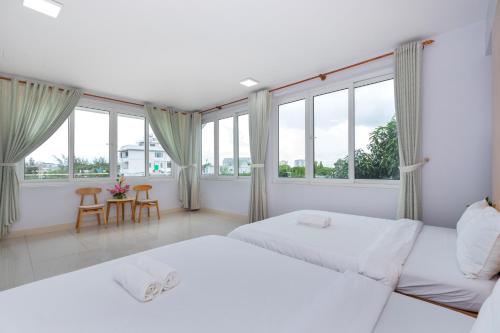 a white bedroom with two beds and windows at Kegotel Luxury Villa - Bãi Tắm Long Cung in Vung Tau