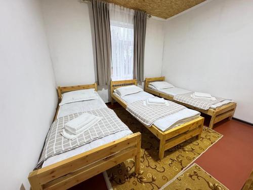 a room with three beds and a window at AI-NUR guest house in Shabdan